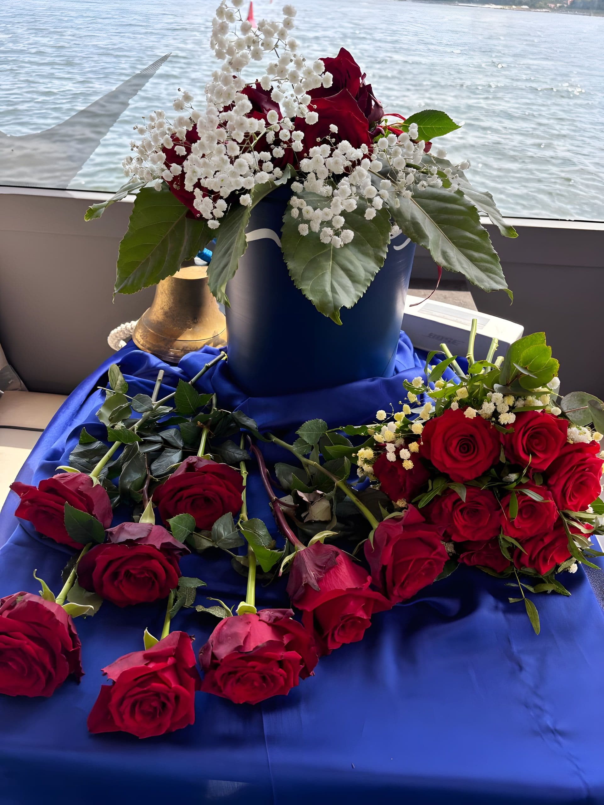 Seeurne mit Rosen, Schleierkraut und Schiffsglocke im Salon eines Schiffes
